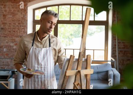 Entspannte glückliche 40s Mann Malerei im Kunststudio. Stockfoto