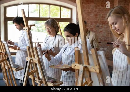 Glücklich fokussierte verschiedene Menschen zeichnen auf Leinwand. Stockfoto