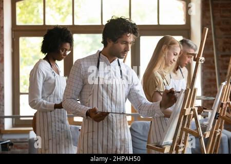 Lächelnde junge, multirassische Menschen zeichnen auf Leinwand. Stockfoto