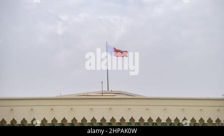 Die Al-Adaam-Nationalflagge von Katar, die über dem Amiri Diwan Parlamentsgebäude in Doha, Katar, fliegt Stockfoto