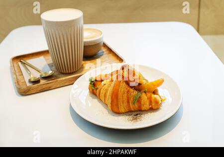 Croissant mit Lachs und Ei auf einem Kaffeetisch. Geringer Fokus. Stockfoto