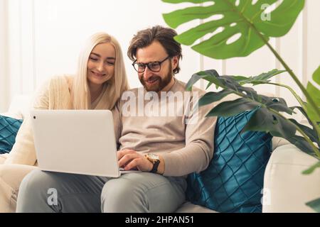 kaukasische Ehepartner kaufen energisch online ein und sehen sich lustige Videos im Internet an. Hochwertige Fotos Stockfoto
