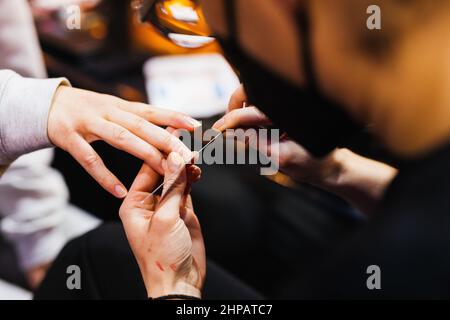 Rust, Deutschland. 19th. Februar 2022. Eine Teilnehmerin des Miss Germany-Wettbewerbs sitzt hinter der Bühne, um ihre Fingernägel zu archivieren. 160 Teilnehmer wurden im September zur sogenannten 'Live Experience' nach Hamburg eingeladen. Gleichzeitig bedeutet diese Änderung, dass es nicht wie üblich 16 Finalisten im Finale geben wird, sondern dass es eine Top 10 geben wird, aus der die neue Miss Deutschland im heutigen Finale ausgewählt wird. Quelle: Philipp von Ditfurth/dpa/Alamy Live News Stockfoto