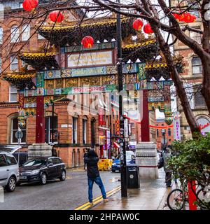 Tourist macht ein Foto an einem typischen regnerischen Tag des Chinatown Torbogen/Tor mit Drachen & Pheonixes dekoriert kann auf Faulkner Street, Mancheste gesehen werden Stockfoto