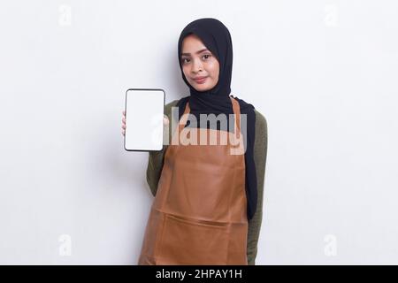 Asiatische muslimische Barista Kellnerin demonstriert Handy auf weißem Hintergrund Stockfoto