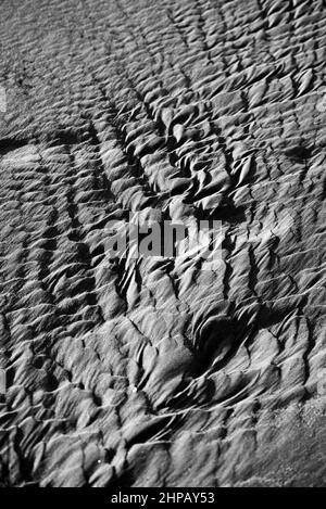 Vertikale Aufnahme einer Düne mit der welligen Oberfläche, in Graustufen gedreht Stockfoto