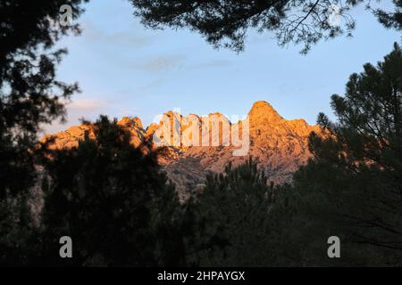 El Yelmo, der Gipfel von La Pedriza vom Wald aus gesehen bei Sonnenuntergang. Stockfoto