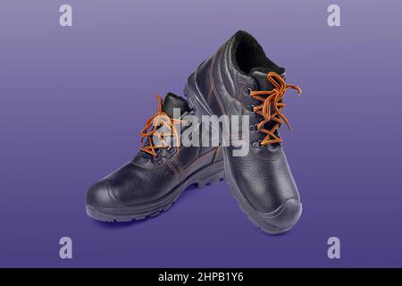 Schwarze warme Stiefel mit orangen Schnürsenkeln, Wanderschuhe, warme Arbeitsstiefel, Herrenschuhe, farbiger Hintergrund Nahaufnahme selektiver Fokus Stockfoto