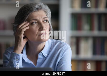 Abgelenkt von Computerarbeit gestresste alte Frau, die in der Ferne schaute. Stockfoto