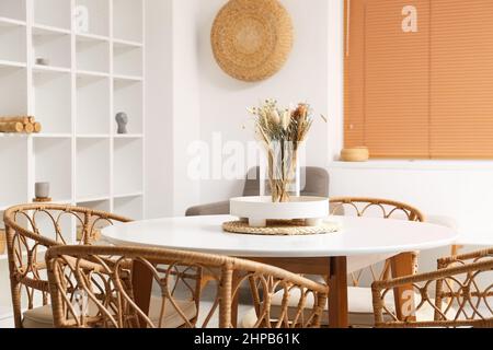 Vase mit getrockneten Blumen und Tablett auf weißem Tisch im Esszimmer Stockfoto