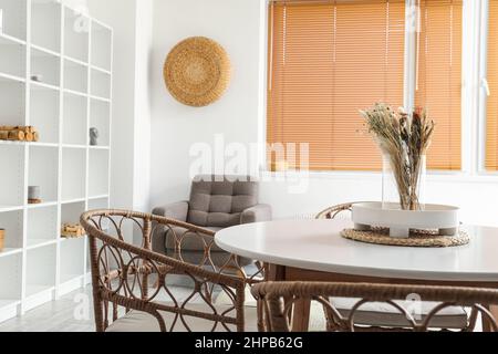 Vase mit getrockneten Blumen und Tablett auf weißem Tisch im Esszimmer Stockfoto