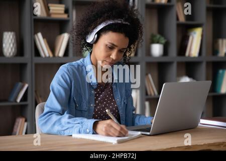 Fokussierte glückliche junge afroamerikanische Frau, die online studiert. Stockfoto