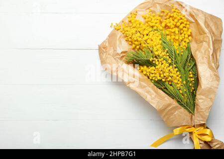 Schönes Bouquet von Mimosenzweigen auf hellem Holzhintergrund Stockfoto