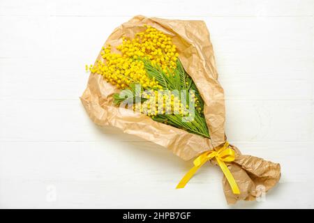 Schönes Bouquet von Mimosenzweigen auf hellem Holzhintergrund Stockfoto