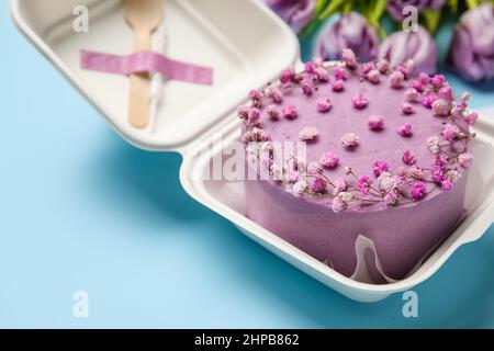 Lunchbox aus Kunststoff mit leckerem Bento-Kuchen auf blauem Hintergrund, Nahaufnahme Stockfoto