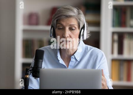 Fokussierte, selbstbewusste Trainerin mittleren Alters, die Lehrvorträge aufzeichnete. Stockfoto