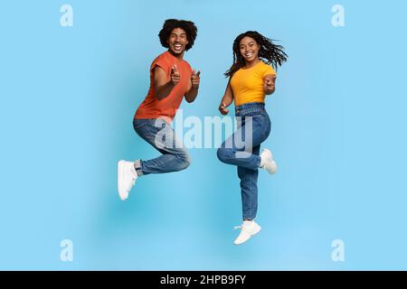 Glückliche afroamerikanische Liebhaber feiern den Erfolg auf Blau Stockfoto
