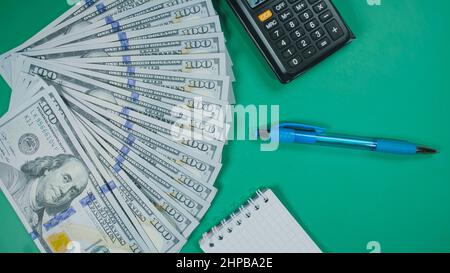 Viele Dollar Geld schaffen Muster, machen Design Form Bild. Draufsicht, flach liegend. Erstellen Sie runden Kreis, machen Design Form Bild. Geldnotendollar, Taschenrechner, Stift, Notizblock auf dem Hintergrund. Stockfoto