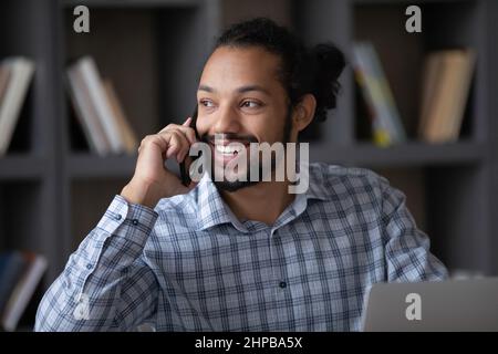 Lächelnder, tausendjähriger, hübscher afroamerikanischer Mann, der zu Hause multitasking. Stockfoto