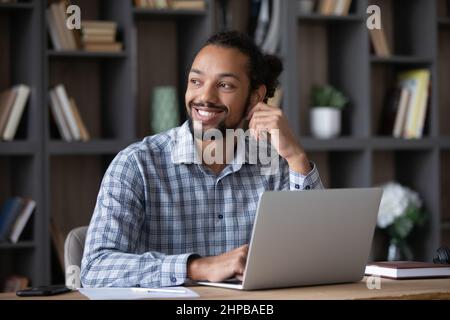 Abgelenkt von Laptop-Arbeit lächelnden afrikanischen Mann in der Ferne zu sehen. Stockfoto