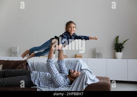 Entspannt glücklich afroamerikanischen Vater heben in der Luft lachende Tochter. Stockfoto