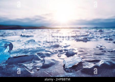 Sonnenaufgang am Baikalsee im Winter. Die Sonne reflektiert sich von der eisigen Oberfläche des Sees. Stockfoto