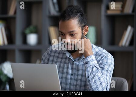 Konzentrierter junger afroamerikanischer Geschäftsmann, der am Computer arbeitet. Stockfoto