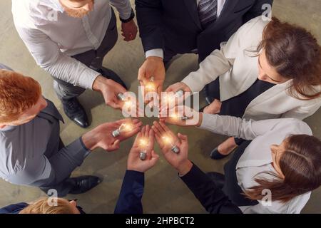 Teamwork und Brainstorming-Konzept mit Geschäftsleuten, die eine Idee mit einer Lampe teilen Stockfoto