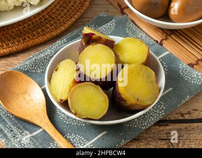 Bing Xin Süßkartoffel in einer weißen Schüssel mit Holzlöffel isoliert auf Matte Draufsicht Stockfoto