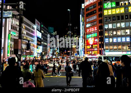 Tokio, Japan - 28. März 2019: Menschen überqueren die Straße in der Innenstadt von Shinjuku in dunkelschwarzer Nacht mit Neon-Nachtlicht Stadtbild und Zeichen ne Stockfoto