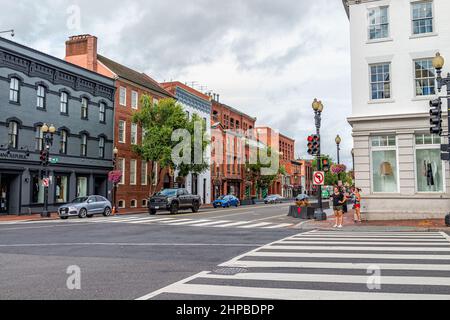 Washington DC, USA - 18. August 2021: Georgetown M Straßenlandschaft mit Geschäften Geschäfte Gebäude in der Nachbarschaft mit Menschen warten darauf, Straße wieder zu überqueren Stockfoto