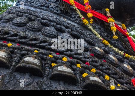 Nahaufnahme der 350 Jahre alten monolithischen Statue von Nandi (Stier) mit den Glocken, die nach täglichen Gebeten mit Blumen geschmückt sind, Chamundi Hill, Mysore, Indien Stockfoto