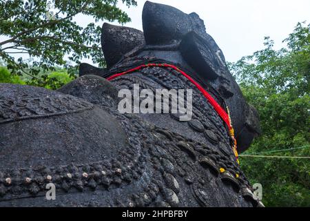 Nahaufnahme der 350 Jahre alten monolithischen Statue von Nandi (Stier) mit den Glocken, die nach täglichen Gebeten mit Blumen geschmückt sind, Chamundi Hill, Mysore, Indien Stockfoto