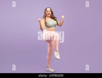 Glad Zufriedene und große europäische Millennial-Frau in Sportbekleidung feiert Gewichtsverlust Erfolg und Sieg Stockfoto