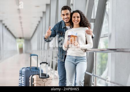 Reisewerbung. Glückliches Junges Arabisches Paar Posiert Am Flughafen, Fröhliches Paar Wartet Flug Am Terminal, Frau Hält Pässe Mit Tickets Und Stockfoto