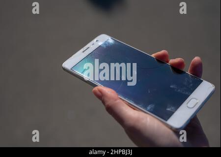 Frau hält Smartphone mit defekten Bildschirm im Freien. Stockfoto