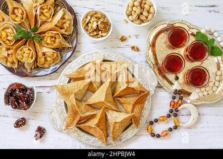 Ramadan Kareem festlich, Fasten, Halal-Essen. Ramadan-Menü: Gemischtes arabisches Pfannkuchen-Katayef und Datteln, Pistazie. Draufsicht flach liegend. Stockfoto