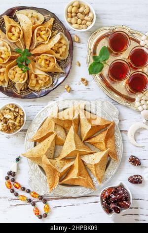 Ramadan Kareem festlich, Fasten, Halal-Essen. Ramadan-Menü: Gemischtes arabisches Pfannkuchen-Katayef und Datteln, Pistazie. Draufsicht flach liegend. Stockfoto