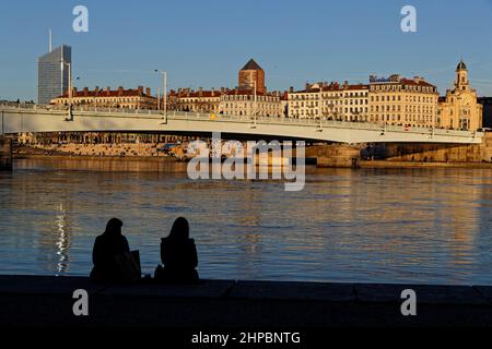 LYON, FRANKREICH, 19. Februar 2022 : Silhouetten junger Menschen am Ufer der Rhone bei Sonnenuntergang. Stockfoto