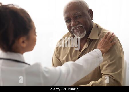 Nahaufnahme einer schwarzen Ärztin, die die Hände eines männlichen Patienten hält Stockfoto