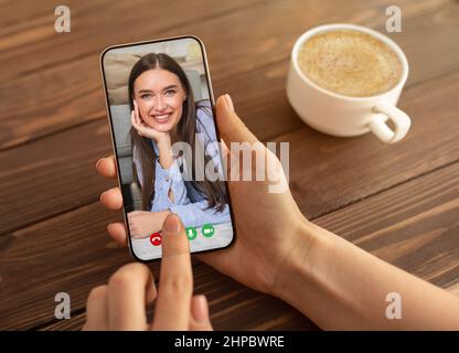 Frau, die ein Smartphone für einen Videoanruf mit einem Freund benutzt, während sie im Café sitzt Stockfoto