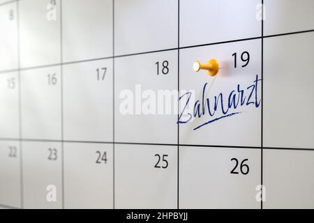 Zahnarztpraxis Konzept in deutscher Sprache. Ein Kalender mit einem Eintrag 'Zahnarzt' und einem Daumennack. Selektiver Fokus. Stockfoto