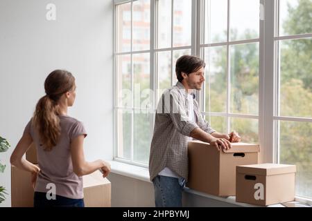 Müde Depression Millennial kaukasischen männlichen und weiblichen in Casual mit Pappkartons blickt aus dem Fenster Stockfoto