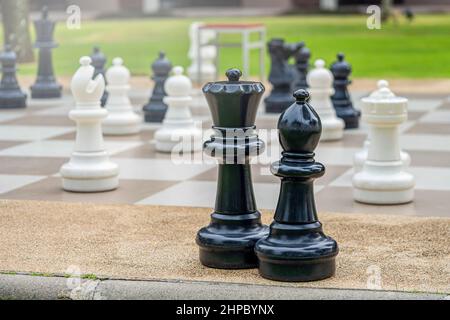 Straßenschach. Große schwarz-weiße Schachfiguren und Spielbrett im Freien aus der Nähe. Stockfoto