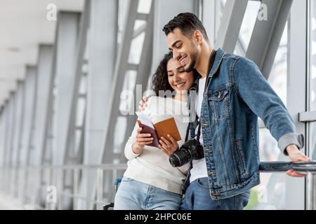 Portrait Von Glücklichen Reisenden Aus Dem Nahen Osten Paar Wartet Am Flughafen, Lächelnd Junge Arabische Ehegatten Halten Pässe Und Tickets Und Warten Auf Flug Bo Stockfoto