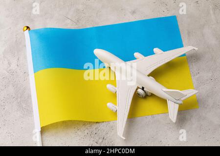 Ukrainische Flagge und Spielzeugflugzeug auf abstraktem Hintergrund, ein Konzept zum Thema Reise in die Ukraine Stockfoto