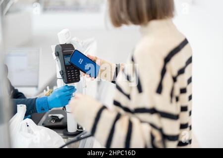 Frau zahlt kontaktlos per Telefon im Supermarkt Stockfoto