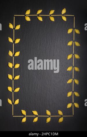 Vielfalt an ungekochten Nudeln, die als Rahmen angeordnet sind, isoliert auf schwarzem Schieferhintergrund, Diät- und Essenskonzept, Draufsicht mit Kopierraum Stockfoto