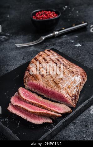 Gegrilltes Flanke Steak BBQ auf einem Marmorbrett. Schwarzer Hintergrund. Draufsicht Stockfoto