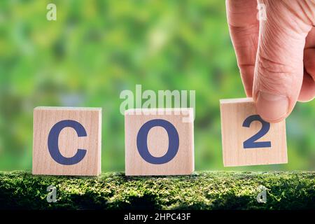 CO2 Würfel auf grünem Hintergrund, das Konzept der Energieeinsparung und Emissionsreduzierung. Senken Sie die Emissionen von CO2, um die globale Erwärmung und den Klimawandel zu begrenzen. Stockfoto